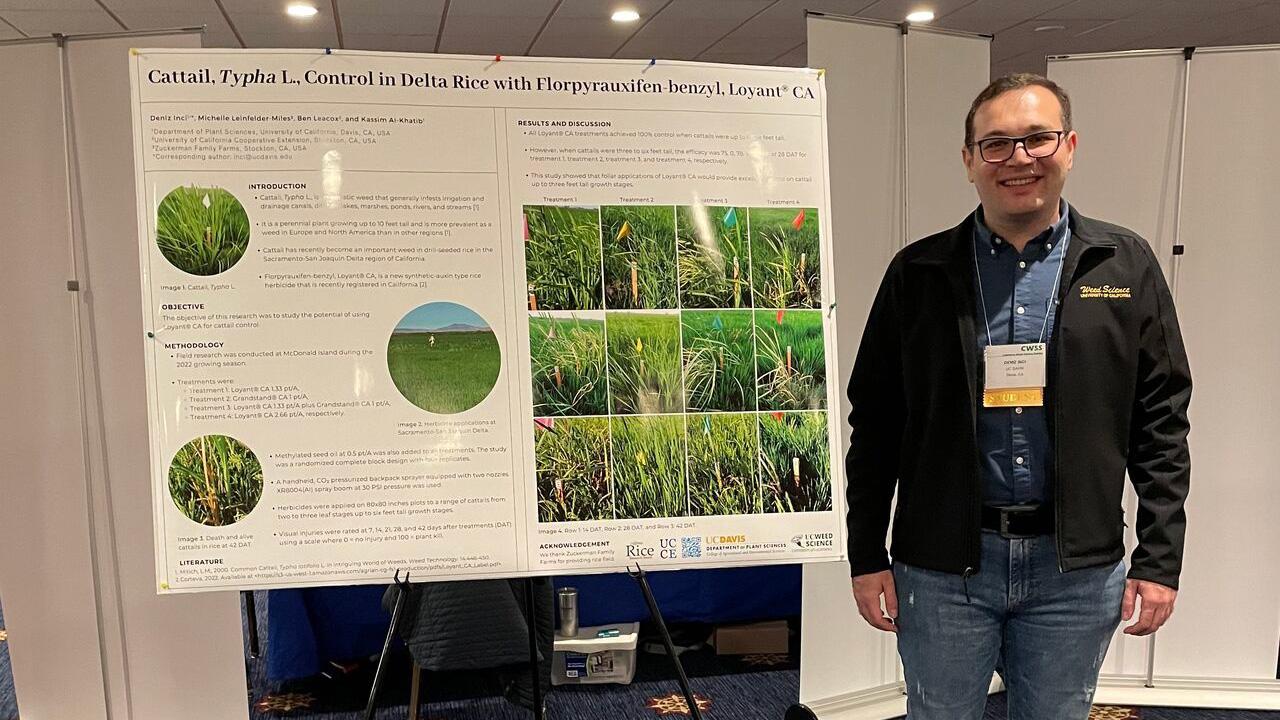 Young man with a scientific poster that reads, “Cattails, Typha L., Control in Delta Rice with Florpyrauxifen"